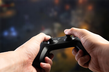 Gamepad in the hands of a gamer. Close-up. The background is a video game on the TV screen. Addictive adventure video games, online games with friends. Game strategy, virtual reality. © Anton