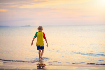 Fototapeta na wymiar Child playing on ocean beach. Kid at sunset sea.