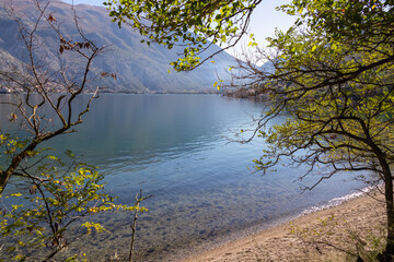 Idyllic beach in coastal town Prcanj with panoramic view of Kotor Bay, Adriatic Mediterranean Sea, Montenegro, Balkans, Europe. Fjord winding along mountain cliffs of Dinaric Alps. Vacation in summer