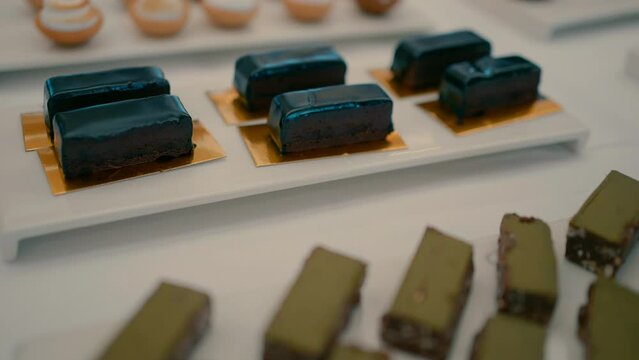A buffet table with different types of desserts. Close-up video of chocolate desserts, vanilla cream, pistachio cream and nuts.
