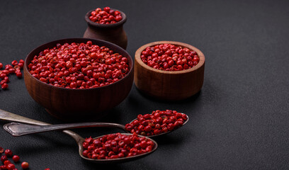 Spice, allspice peas of red or pink color in a wooden bowl