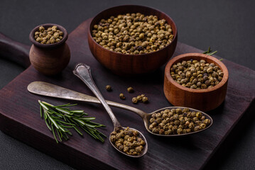 Spice, allspice green in a wooden bowl on a black concrete background