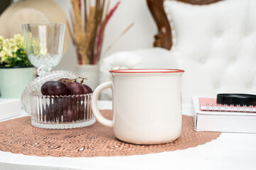 A white blank enamel mug standing out on a mat with some decorations placed around it