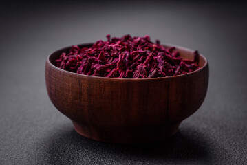 Dried beets in small slices in a wooden bowl on a black concrete background