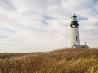 White beautiful lighthouse on a high hilly ocean shore. Desert place. The beauty and grandeur of pristine nature. Tourism, construction, architecture, nature, excursions.