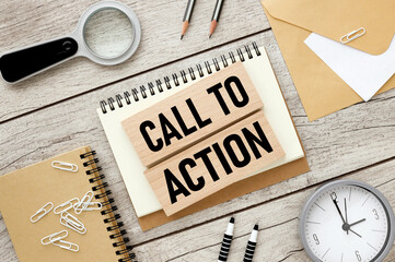 Call to Action. two wooden blocks with text on an open notepad.