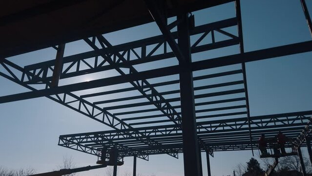 The steel structure is under construction. Installation of metal halls. Work at height. A sunny day at a construction site
