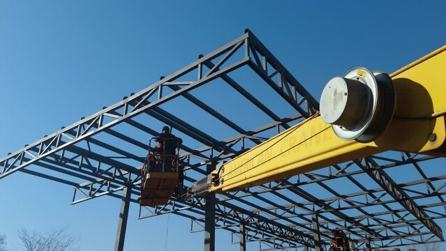 The steel structure is under construction. Installation of metal halls. Work at height. A sunny day at a construction site