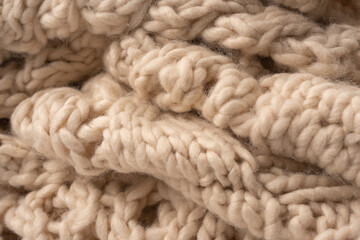 A fragment of beige knitted fabric, knitted from white sheep wool.
