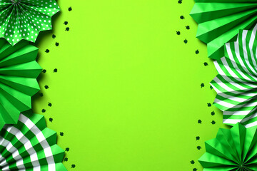 Frame of green folding paper fans and clover leaves confetti on green background. St. Patrick's Day banner template, cover, greeting card mockup.