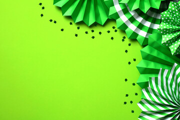 St. Patrick's Day banner design. Folding paper fans and shamrock confetti on green background.