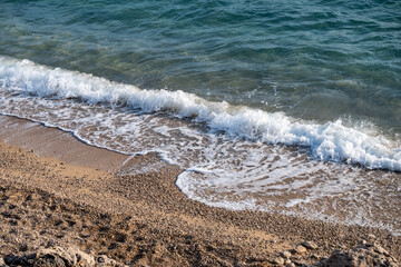Waves splashing sand beach of Brac island, Croatia during beautiful summer sunset creating white foam