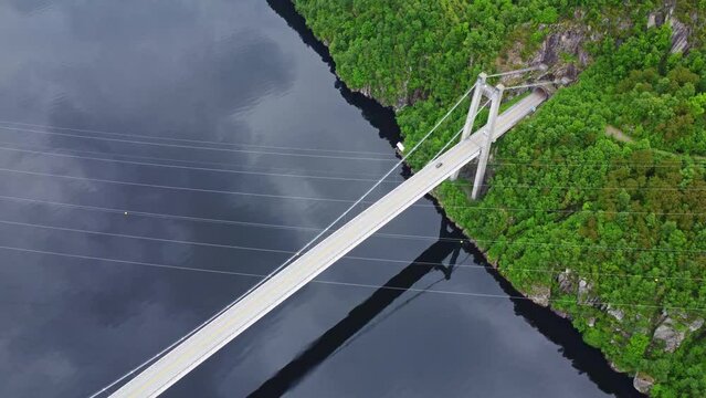 Aerial flight over the Fedafjorden bru bridge with crossing power lines and a tunnel portal	
