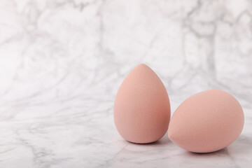 Beauty blender on light marble background. Cosmetics, makeup application tool. Beauty concept. Copy space. Place for text.