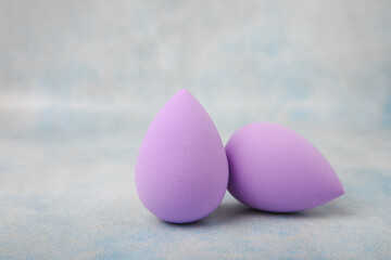 Beauty blender on a blue marble background. Cosmetics, makeup application tool. Beauty concept. Copy space. Place for text.