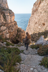 Fototapeta na wymiar Woman walking down a ravine leading to the mediterranean sea in Malta