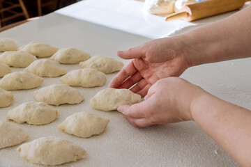 Yeast dough is made homemade buns filling potatoes on a white countertop.