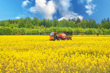 Fototapeta premium Agricultural machinery spraying crops rapeseed with pesticides in spring.