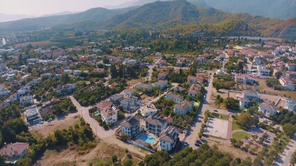 Fototapeta premium Aerial panorama of small resort town. Hotels, houses and roads. Green hills around. Mountain landscape. Photography