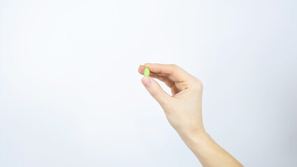 Green medical capsule in human hand. Medicine treatment of diseases, viruses, antibacterial therapy, food supplement. White background Space for text