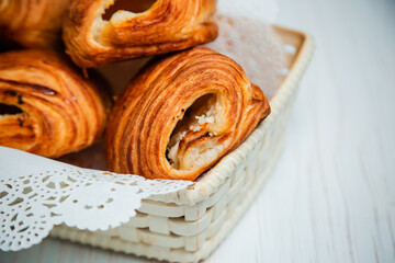 Fototapeta premium Buns with cottage cheese in a white basket with a lacy napkin. Sweet pastry.