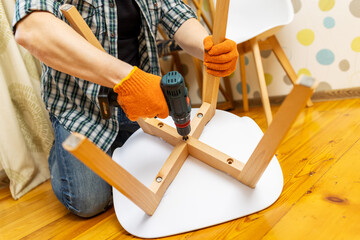 Assemble furniture. Man assembling chair. Furniture assembler with drill