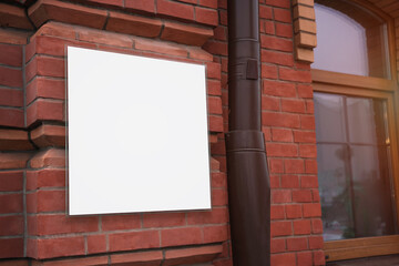 White empty signboard mounted on brick wall of building
