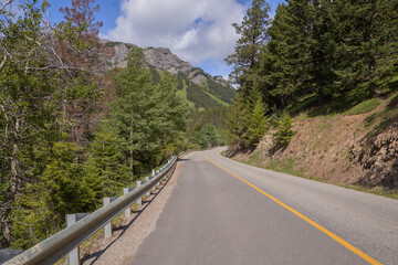 Curved empty country road  passing through forest and green mountains in summer. Asphalt highways and mountains under the blue sky. Traveling Banff, Alberta, Canada. 