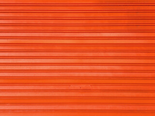 Orange horizontal metal slats wall background. Orange painted wall. Intense orange texture and full...