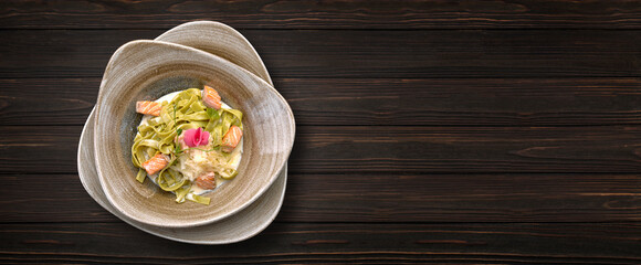 Pasta with trout, cheese and sauce, on a plate, on a wooden background