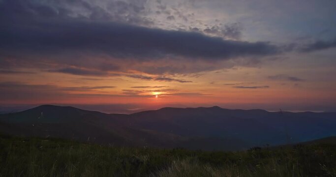 Amazing time lapse video sunrise in the mountains. The sun rises over a mountain range under dramatic, swirling clouds
