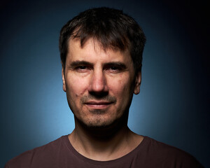 Fototapeta premium Portrait of a 42-year-old brunette man on a dark background with bright illumination