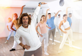 Group of multinational happy adult people enjoying active dance movement in modern studio