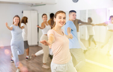 Smiling young adult couples dancing together in pairs and practicing movements in modern...