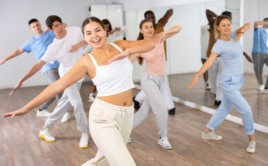 Happy active energetic multiracial dancers of different ages dancing aerobics at lesson in modern...
