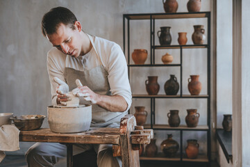 Young man working with clay on potter's wheel