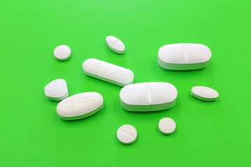 Set of drugs and white pills on a green background