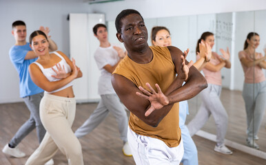 Group of young adult diverse active dancers in sportswear with crossed hands during dance exercise...