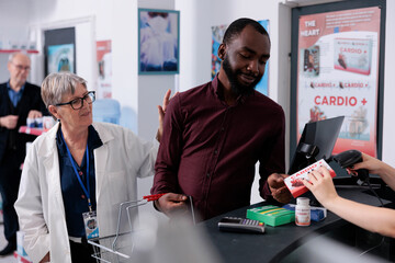 African american client putting pharmaceutical products on counter, preparing to pay for treatment. Adult customer taking boxes of pills and supplements from drugstore, medicine service