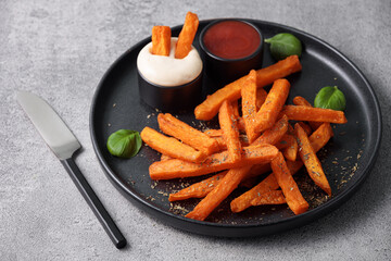 Sweet potato sticks in a black plate served with mayonnaise and ketchup sauce. Vegetarian food and healthy eating concept.