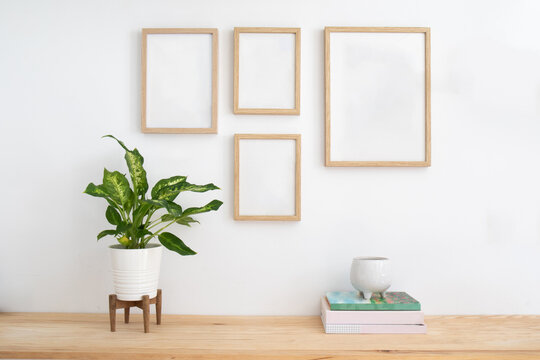 Home decoration still life. Wooden desk table, houseplant, books and a set of empty picture frames mockup, Scandinavian decoration. Home office concept. Elegant space. Gallery wall