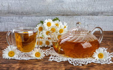 herbal chamomile tea and flowers. teapot and tea glass.