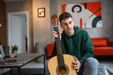 One man caucasian male teenager with classical guitar at home