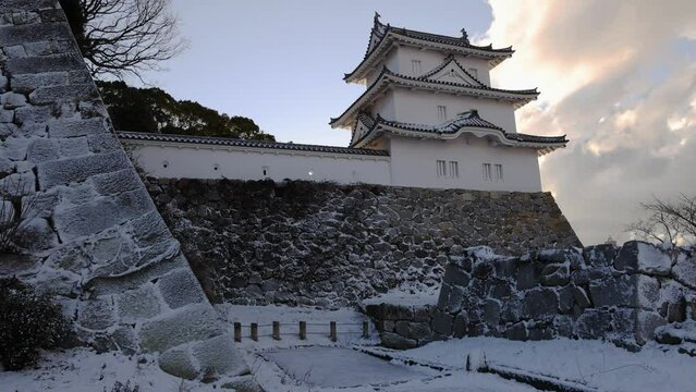 Historic tower atop snow covered stone walls of Japanese castle on winter morning