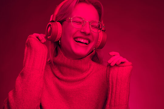Portrait of a happy woman enjoying music. Monochromatic picture. Viva magenta.