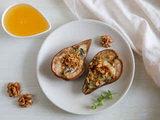 Homemade baked pears with blue cheese, nuts and honey on a plate. French cuisine. Keto diet. Vegetarian lunch. Top view