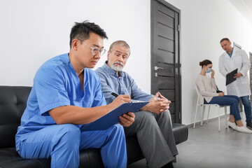 Doctor with clipboard consulting senior patient in clinic