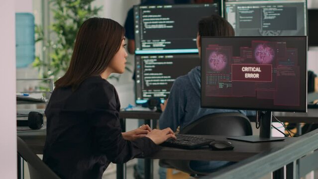 Diverse team of coders having server hacked and system crash, running critical error message flashing on screen with multiple monitos. Displaying hacking alert warning, cyber crime.