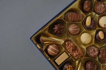 Assorted chocolate candies in a box on a gray background. Milk chocolate candy.Sweets and desserts.Sweets box in assortment