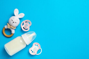 Flat lay composition with pacifiers and other baby stuff on light blue background. Space for text